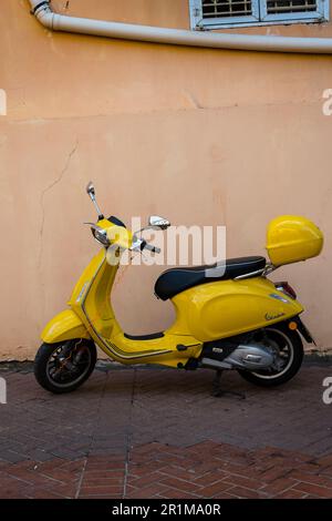 Scooter giallo brillante su uno sfondo chiaro e di colore caldo Foto Stock