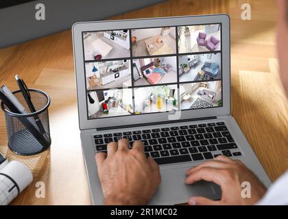 Uomo che controlla telecamere CCTV a tavolo, primo piano. Sistema di sicurezza domestica intelligente Foto Stock