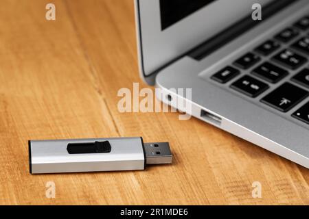 Computer portatile moderno e unità flash usb su un tavolo di legno, guardaroba Foto Stock