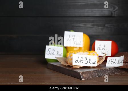 Prodotti alimentari con etichette di potere calorifico su tavola di legno, spazio per testo. Concetto di perdita del peso Foto Stock