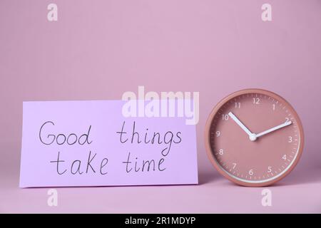 Carta con frase buone cose prendere tempo e orologio su sfondo rosa. Citazione motivazionale Foto Stock