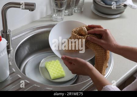 Piastra di pulizia donna con asciugamano in cucina, primo piano Foto Stock