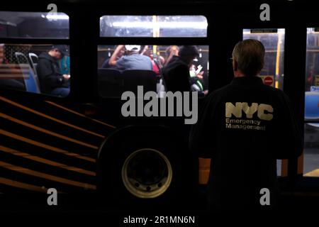 New York, Stati Uniti. 14th maggio, 2023. Un ufficiale di NYC guarda come richiedenti asilo sono trasferiti via autobus urbano dal terminal degli autobus di Port Authority a una struttura abitativa il 14 maggio 2023 a New York City, USA. Dopo essere arrivati dal confine tra Texas e Messico e dopo essere stati processati dai funzionari di New York City, i migranti vengono inviati a varie strutture abitative nei quartieri di New York. Nei prossimi giorni il Roosevelt Hotel fornirà inizialmente un numero limitato di posti letto e successivamente funterà da centro di accoglienza e supporto per i migranti. (Foto di John Lamparski/Sipa USA) Credit: Sipa USA/Alamy Live News Foto Stock