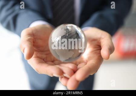 L'uomo d'affari fortunato tiene il globo di vetro con i continenti nelle mani Foto Stock