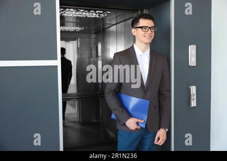 Un giovane uomo d'affari uscendo dall'ascensore moderno Foto Stock