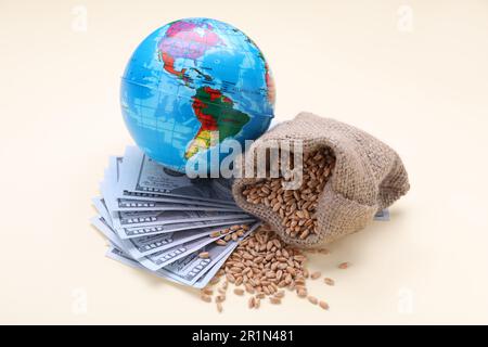 Concetto di importazione ed esportazione. Globo, sacchetto di grani di grano e banconote su sfondo beige Foto Stock