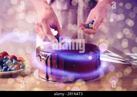 Donna che decora fresco delizioso torta di cioccolato fatta in casa con bacche a tavola, primo piano gustoso dessert per la cena di Natale Foto Stock