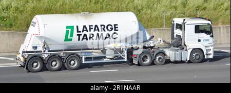 Vista laterale Lafarge porta polvere di cemento sfuso su rimorchio autocisterna articolato trainato da autocarro hgv bianco che guida lungo l'autostrada M25 Essex Inghilterra UK Foto Stock