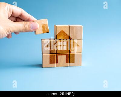 Investimenti immobiliari, risparmio immobiliare, acquisto casa finanziaria e concetti ipotecari. Blocco di cubo di legno, l'ultimo pezzo di puzzle in mano, mettendo su th Foto Stock