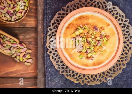 Cucina araba; tradizionale dessert egiziano 'Om Ali' o 'Umm Ali' di pane ammollato, latte e carico di noci arrosto e uvetta. Vista dall'alto con primo piano. Foto Stock