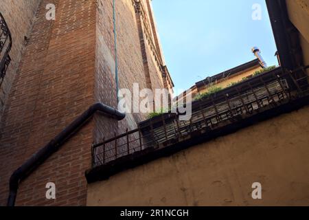 Piccolo balcone con piante in vaso inserito in un vicolo ombreggiato in una città italiana al tramonto Foto Stock