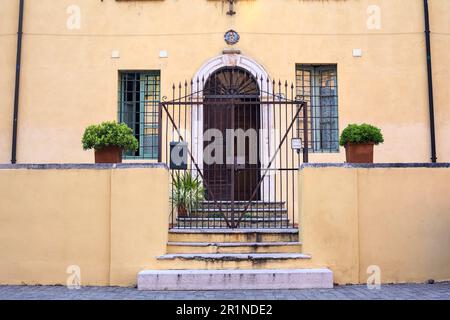 Porta dietro un cancello accanto a una scala in una piazza in una città italiana Foto Stock