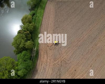 Veduta aerea del trattore agricolo che lavora in un campo in preparazione alla piantagione nell'Herefordshire rurale adiacente al fiume Wye - Regno Unito nel maggio 2023 Foto Stock