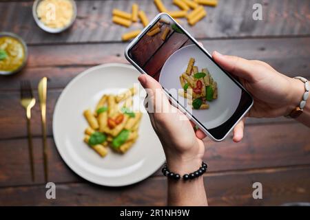 Vista dall'alto del blogger che fa foto di cibo su un tavolo di legno sullo smartphone Foto Stock