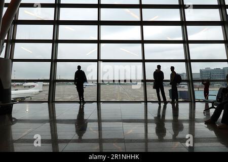 I passeggeri in attesa di partenza all'aeroporto internazionale Vnukovo di Mosca, si godono la vista dall'ampia finestra panoramica fino al campo aerodinamico Foto Stock