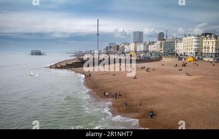Una vista sulla spiaggia e sul lungomare di Brighton, dal molo di Brighton, verso le rovine del vecchio West Pier e della torre i360 a East Sussex, Regno Unito. Foto Stock