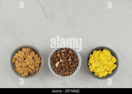 Cereali da colazione in ciotole su uno sfondo di legno chiaro. Fast food. Vista dall'alto. Spazio per il testo. Foto Stock