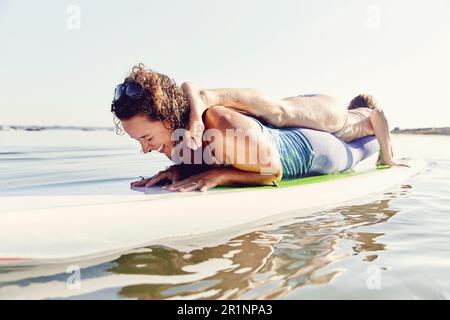 Due giovani donne che fanno yoga su una tavola di pagaia standup Foto Stock