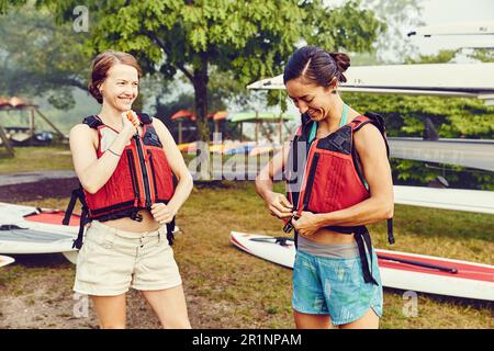 Due giovani donne che si preparano per andare in stand paddle board Foto Stock