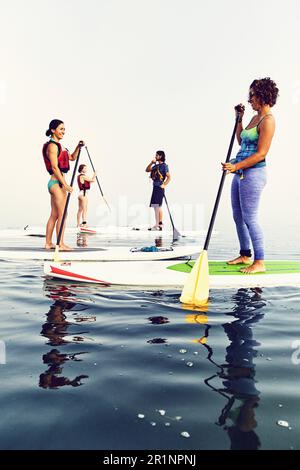 Un gruppo di pagaianti in standup su una mattina nebbiosa all'alba Foto Stock