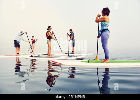 Un gruppo di pagaianti in standup su una mattina nebbiosa all'alba Foto Stock