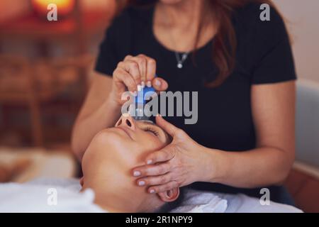 Donna che ha un massaggio di concubatura del viso in salone Foto Stock