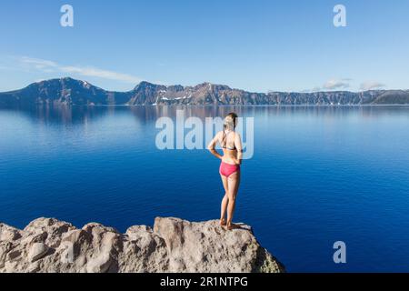 Una giovane donna si trova sul bordo del Crater Lake. Foto Stock