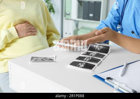 Medico che mostra un'immagine ecografica a una donna incinta in clinica, primo piano Foto Stock