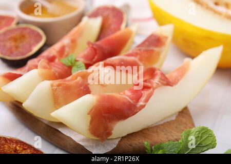 Gustosi meloni, jamon e fichi serviti su asse di legno, primo piano Foto Stock