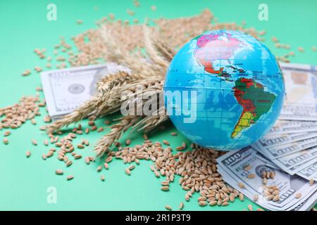 Concetto di importazione ed esportazione. Globo, grani di grano, e banconote su sfondo verde, primo piano Foto Stock