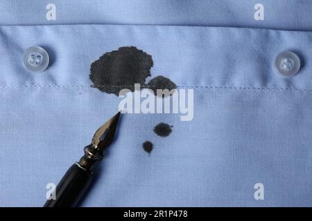 Macchie di inchiostro nero su camicia e penna blu chiaro, vista dall'alto. Spazio per il testo Foto Stock