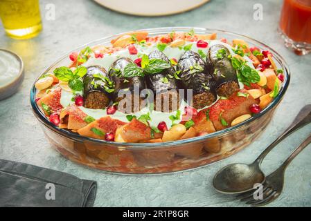 Piatto tradizionale mediorientale 'Fattet Makdous'. E' un gustoso strato composto da melanzane fritte farcite con carne tritata speziata e salsa di pomodoro. Foto Stock
