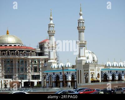 Cairo, Egitto, aprile 26 2023: Una bella moschea bianca nel nuovo Cairo Egitto con più cupole e minareti accanto a un edificio in costruzione con un Foto Stock