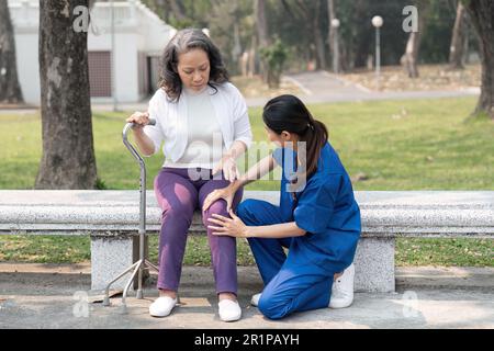 Un'infermiera che controlla il ginocchio degli anziani che si occupa del parco ospedaliero Foto Stock