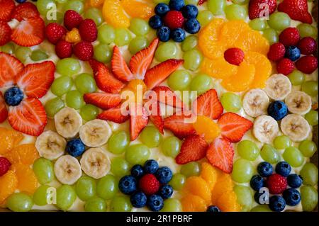Torta sormontata con vari frutti a forma di fiori. Foto Stock