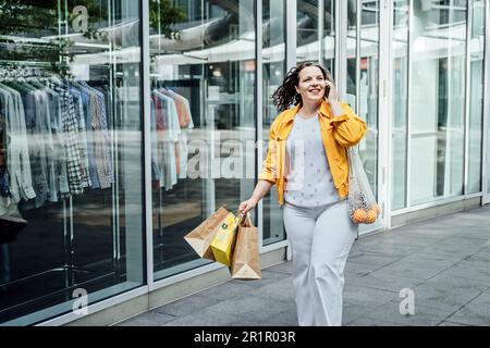 Allegro felice più grande donna curvy parlare al telefono all'aperto. Ritratto all'aperto di felice sorridente candida più dimensione donna con telefono cellulare in città Foto Stock