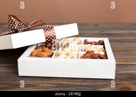 Varie varietà di noci giacendo in scatola di carta su sfondo tavolo. Vista dall'alto. Cibo sano. Primo piano, spazio di copia, vista dall'alto, disposizione piatta. Noce, pistacchi Foto Stock