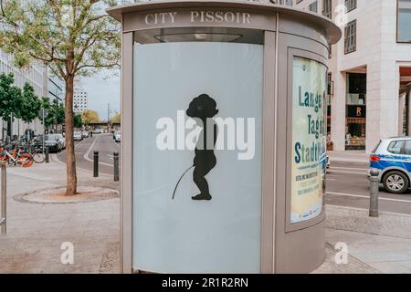 L'immagine cattura un bagno pubblico, noto anche come pissoir città, situato in un vivace ambiente urbano. La fotografia offre uno sguardo all'interno dell'infornato Foto Stock