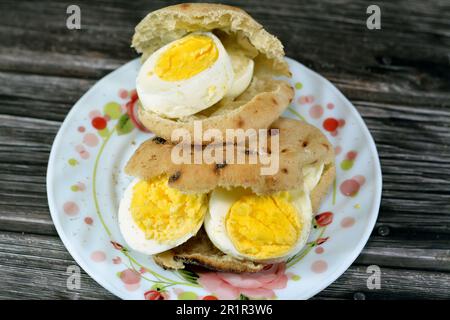 Mini tradizionale piatto di pane egiziano con crusca di grano e farina, piccolo Baladi di Aish o piccolo pane ripieno e ripieno di fette di uova sode, un Foto Stock