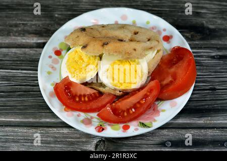 Mini tradizionale piatto di pane egiziano con crusca di grano e farina, piccolo Baladi di Aish o piccolo pane ripieno e ripieno di fette di uova sode, un Foto Stock