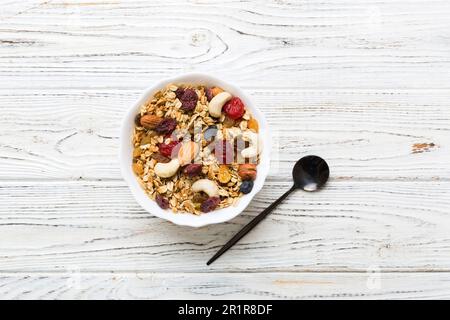 Cucinare una sana colazione. Granola con vari frutti secchi e noci in una ciotola. Il concetto di un dessert sano. Piano di giacitura, vista dall'alto con sp. Copia Foto Stock