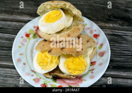Mini tradizionale piatto di pane egiziano con crusca di grano e farina, piccolo Baladi di Aish o piccolo pane ripieno e ripieno di fette di uova sode, un Foto Stock