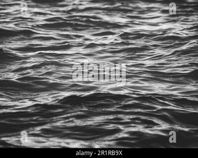 L'acqua bianca e nera increspa la superficie dello sfondo. Foto Stock