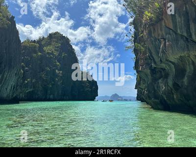 Scogliere calcaree e barche ormeggiate all'ingresso della Grande Laguna, El Nido, Palawan, Mimaropa, Luzon, Filippine Foto Stock