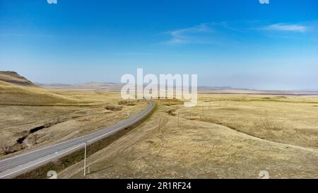 Veduta aerea di una strada che conduce attraverso la terra desertica e le colline. Sabbia gialla vista terra morbida. Foto Stock