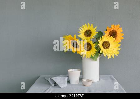 Mazzo di girasoli in vaso su un tavolo con stoviglie in ceramica e un tovagliolo Foto Stock
