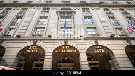 Londra - Maggio 2023: L'hotel di lusso a 5 stelle Ritz London con gli iconici taxi neri di Londra si muove sfocato di fronte all'ingresso principale. Foto Stock
