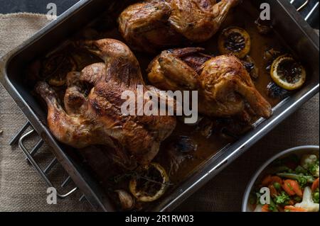 Pollo al limone al forno con aglio, cipolle e timo in una teglia da forno Foto Stock