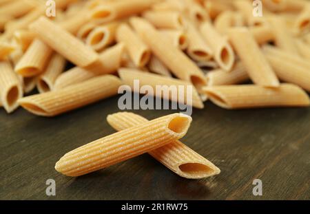 Primo piano di superficie rigata di penne rigate essiccate sparse su tavola di legno Foto Stock