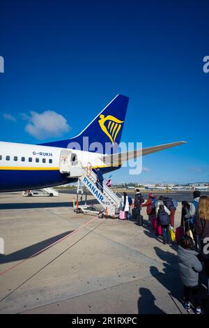 I passeggeri che si accingono a bordo dei gradini posteriori del Boeing 737-800 Ryanair G-RUKH all'aeroporto di Lisbona Foto Stock